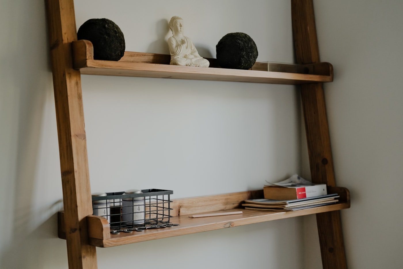 Houten ladderkast die tegen de muur leunt met boeken en potjes erop
